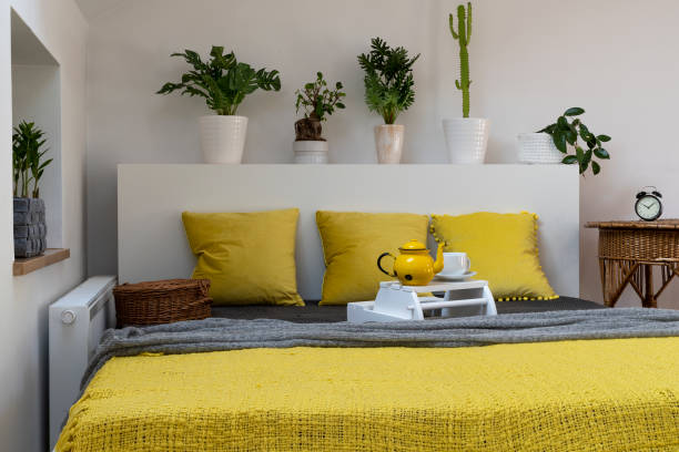 istock Comfortable bed in bedroom with yellow pillow and blanket and boho decoration. 2119546257
