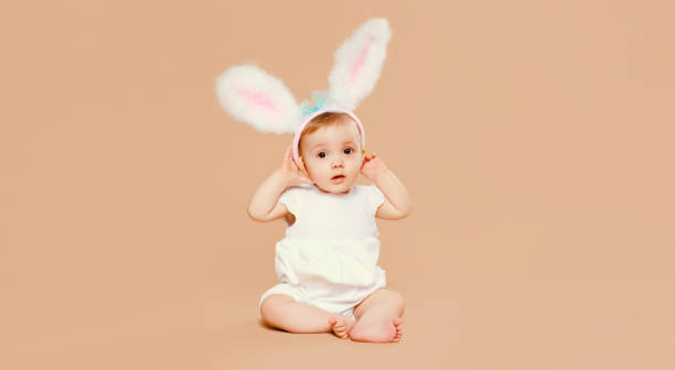 Portrait cute baby with easter rabbit ears sitting on brown studio background