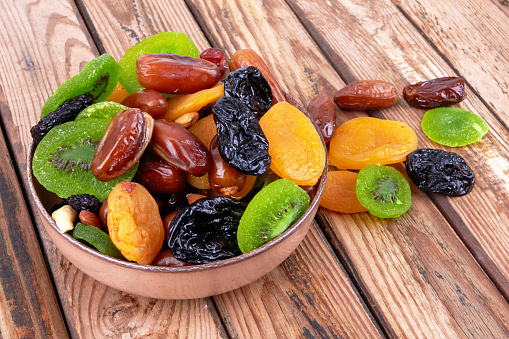 Dry fruits in bowl on a wooden background