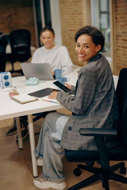 istock Pretty female freelancer working on digital tablet and use phone while sitting in modern coworking 2119587185