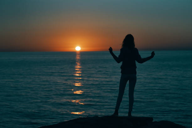 female silhouette gesturing with hands sunset sea model. High quality photo