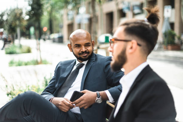 istock business men sharing idea on the bench 2119628194