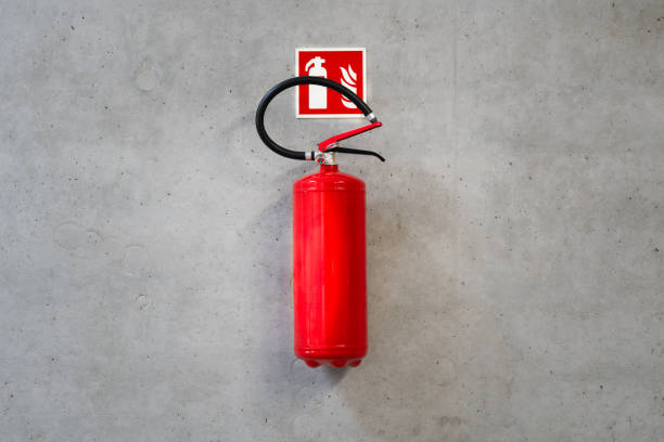 Red fire extinguisher hanging on gray concrete wall.