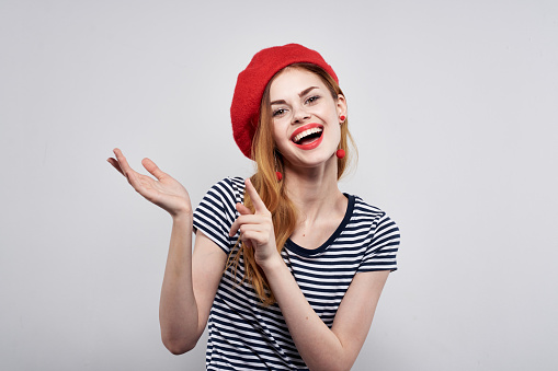 beautiful woman in a striped t-shirt red lips gesture with his hands light background. High quality photo