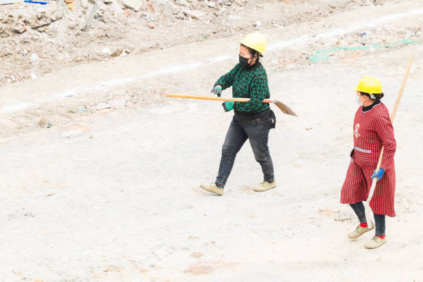 On a sunny day on February 20, 2024, two female workers were walking back with shovels on the road under construction in Shuangliu District, Chengdu, Sichuan Province, China