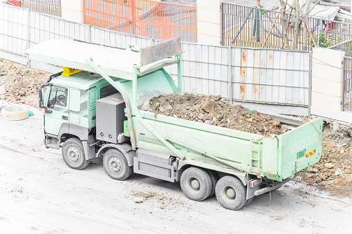 On a sunny day on February 18, 2024, in Chengdu, Sichuan Province, China, an excavator was cleaning up excess soil on the roadside under construction, and then loading the excess soil onto a large truck.