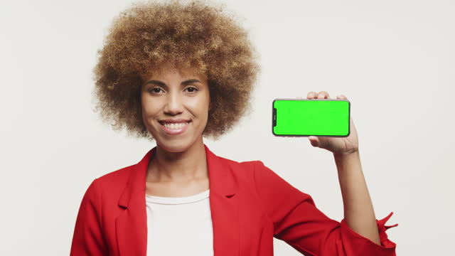 Confident Businesswoman Presenting Smartphone with Green Screen