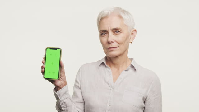 Elderly Woman Holding Smartphone with Green Screen