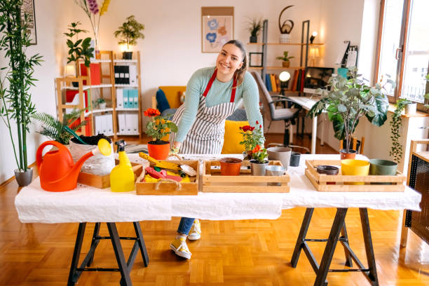istock Young woman wearing apron while potting flowers at home 2119693403