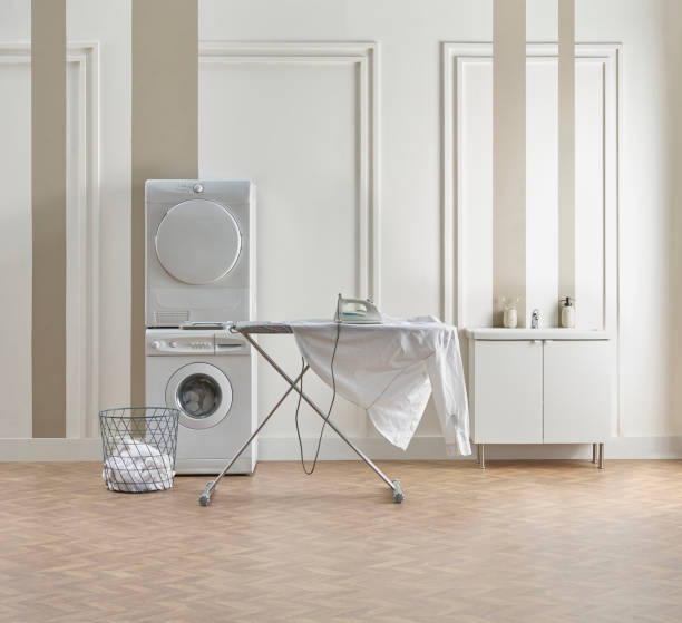 istock Washing dryer machine and ironing table interior style, laundry room, white and brown vertical wall background. 2119709998