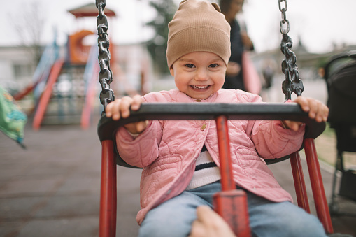 Smiling toddler girl having fun on a swing.