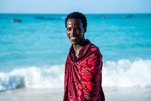 Zanzibar, Tanzania - January 02,2024: Maasai warrior dressed in traditional clothes on sand beach of Zanzibar island.
