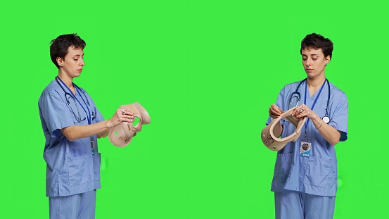 Specialist presenting cervical neck collar used for physical therapy and trauma after an accident or fracture, greenscreen backdrop. Nurse shows orthopedics brace to help with spine injury. Camera B.