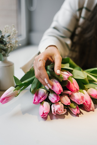 Woman's hand on pink will flowers at a table in a cafe
