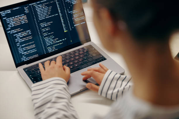 istock Close up of female software engineer writing code on laptop with screens setup in coworking 2119790111