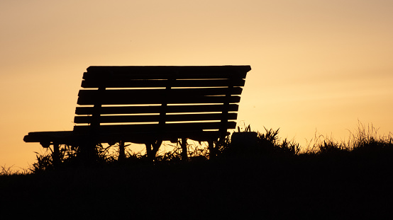 Silhouette of a bench lit by the setting sun
