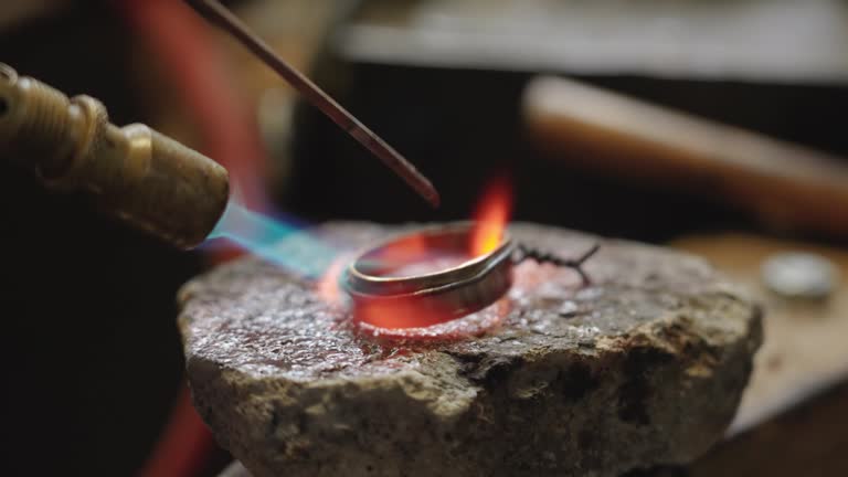 Craftsman soldering the tip of the scabbard in the workshop