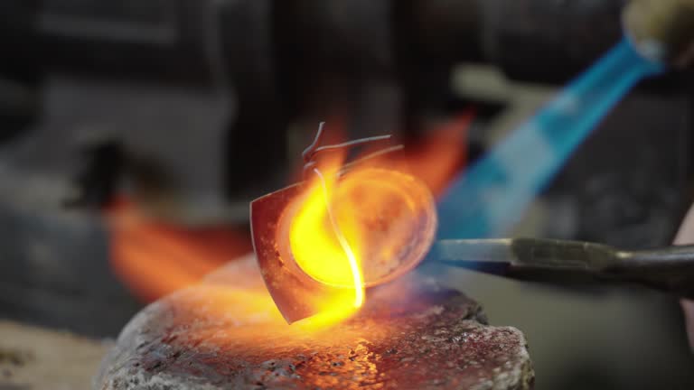 Craftsman soldering the tip of the scabbard in the workshop