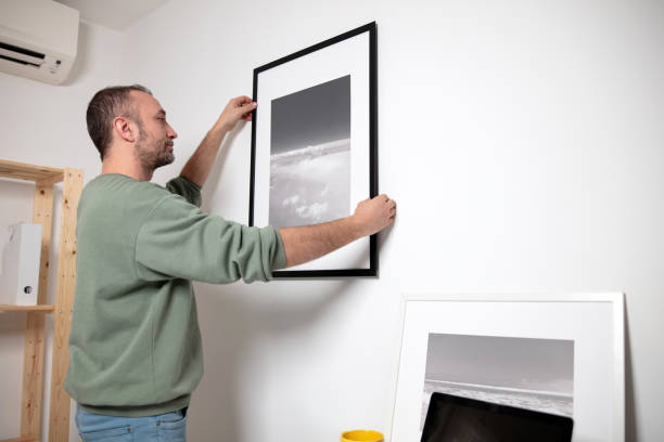 istock Man hanging pictures on the wall. 2119834863