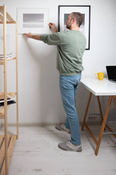 istock Man hanging pictures on the wall. 2119835896