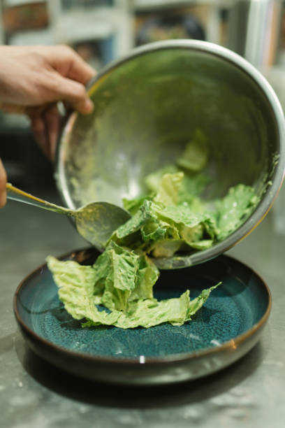 istock Culinarian serves ready lettuce salad with spoon from bowl 2119838541