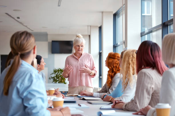 istock Mature female CEO explaining strategy to colleagues during meeting at office 2119840671