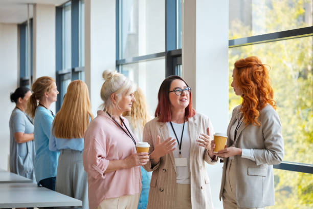 istock Businesswomen discussing with each other while standing in office during conference event 2119860897