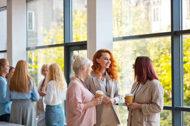 istock Businesswomen discussing with each other while standing in office during seminar 2119862474