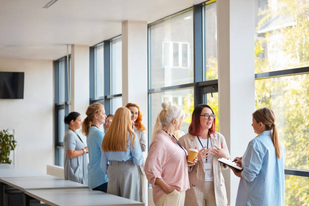 istock Female business colleagues discussing with each other while standing in workplace during networking event 2119867848