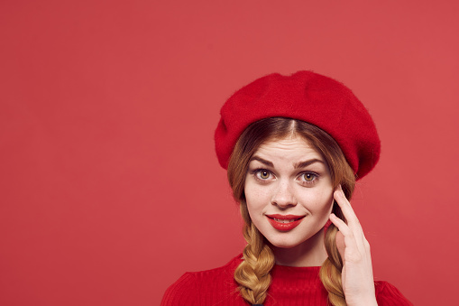 cheerful woman with a red cap on his head glamor red background. High quality photo