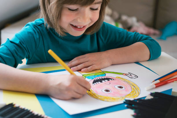 istock Cute boy draws a portrait of a child with missing teeth 2119874916