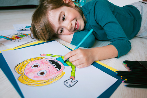 Cute smiling boy with missing teeth drawing a self-portrait
