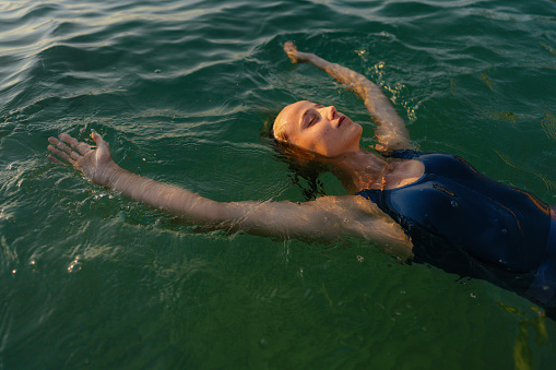 Portrait of a young athlete woman, relaxing on the sea surface after doing numerous laps in the sea