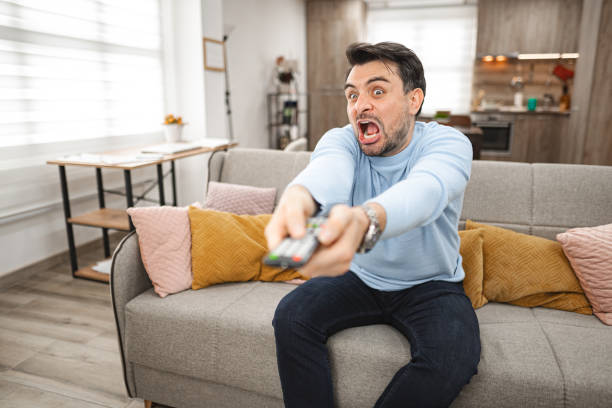 istock Angry man changing channels on TV 2119884176