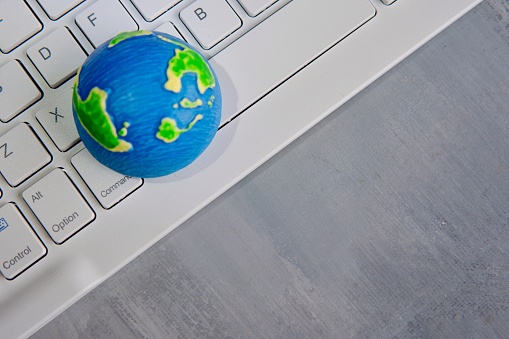 A globe on a white computer keyboard with copy space. Global communication, computer network, globalization concept.