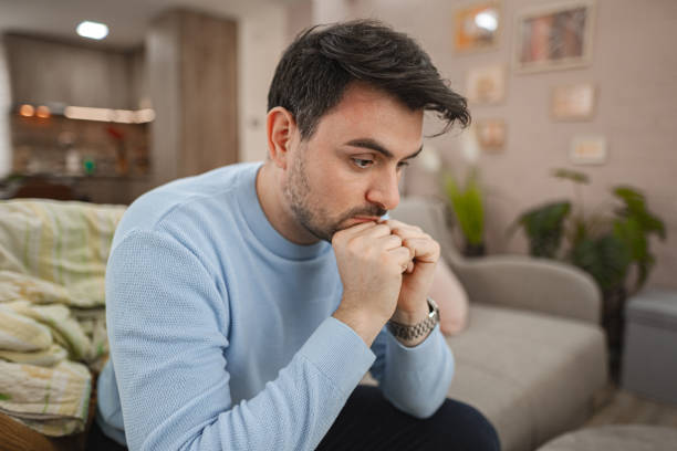 istock Distraught man sitting on a sofa at home 2119884730
