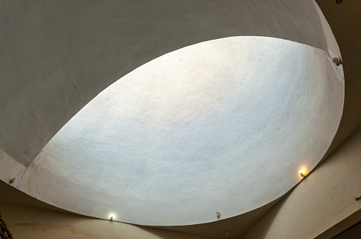 A large white dome with a hole in the middle. The hole is illuminated by sunlight. The dome is made of concrete and has a circular shape