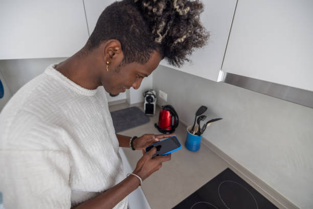 istock Man online shopping. using his phone in the kitchen 2119909586