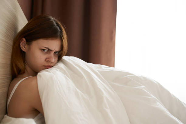 istock upset woman under blanket bed and open window curtains model side view 2119916424