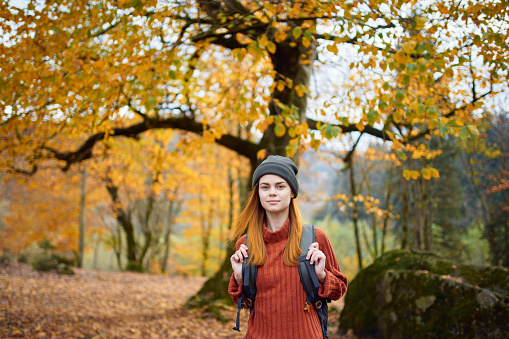 traveler with a backpack resting in the autumn forest in nature near the trees. High quality photo