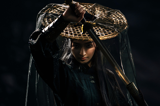 Dramatic studio portrait of a Chinese swordswoman in period drama traditional Hanfu