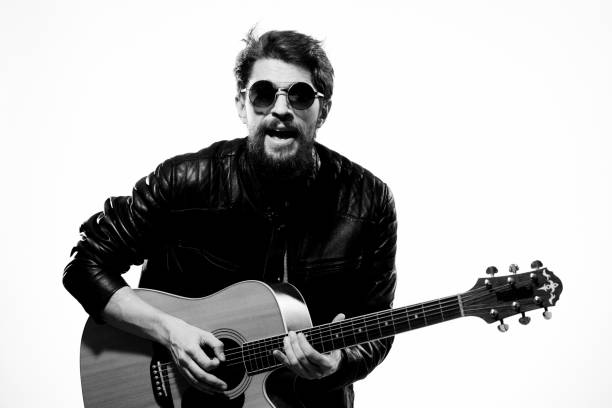 istock A man plays the guitar in a black leather jacket with sunglasses on a light background 2119942035