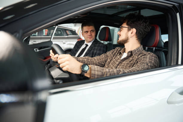 istock Man discussing new car with salesman sitting in front seats inside automobile 2119954384
