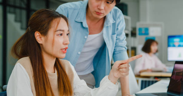 istock Asian manager instructs a new hire, demonstrating the collaborative spirit in a tech-focused office that values accessibility and sustainability. ESG sustainable business office. 2119958744