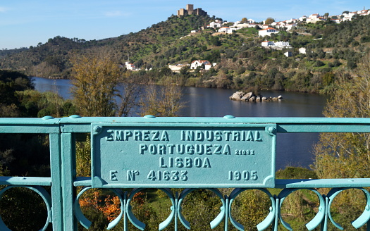 Information plaque at the entrance to Belver Bridge, on the railing of the bridge, Tagus River and hill-top Belver Castle in the background, Belver, Portugal