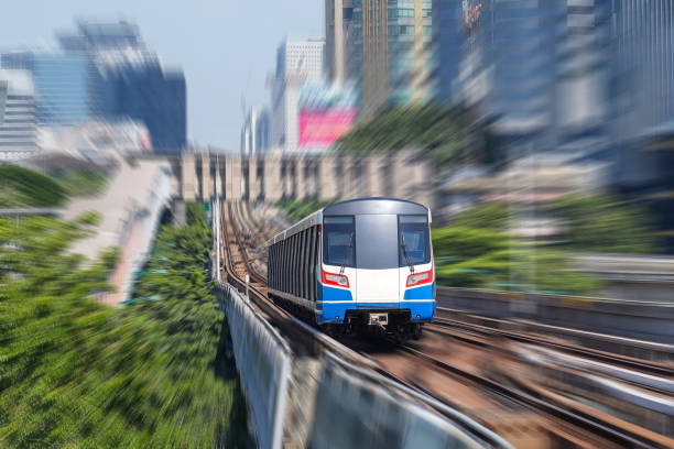 istock Electric train rushes motion speed blur effect among trees and a park in a metropolis 2119965196
