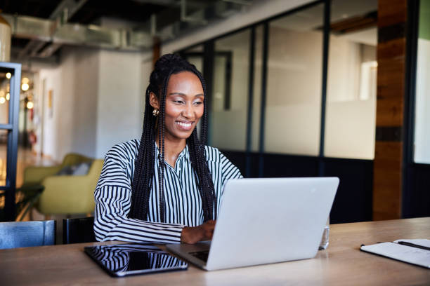 istock Smiling young businesswomen using a laptop at an office table 2119984668