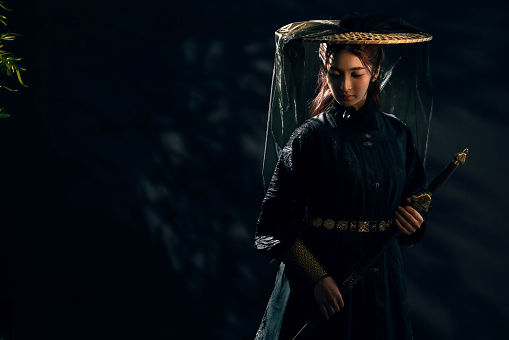 Dramatic studio portrait of a Chinese swordswoman in period drama traditional Hanfu