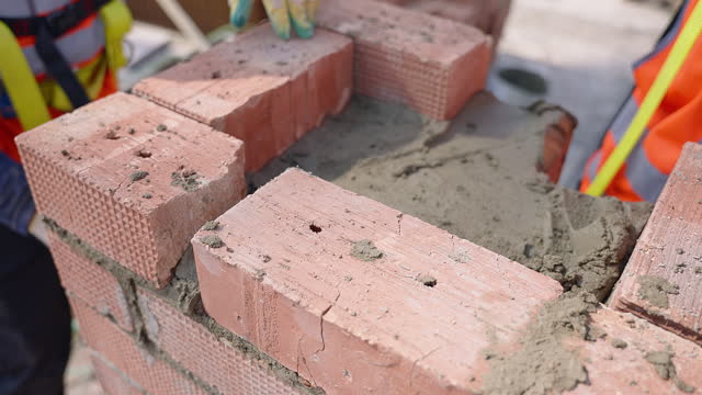 Construction worker laying bricks on brick wall using building material
