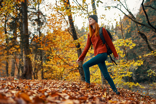 beautiful woman with a backpack in the park on nature landscape fallen leaves bottom view. High quality photo